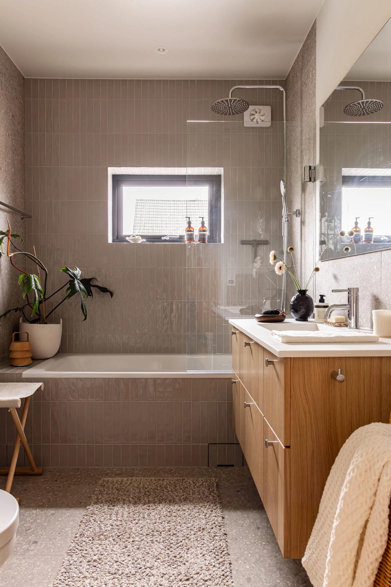 Bad i skandinavisk stil med et organisk preg over innredningen. Baderomsinnredningen i treverk og terrazzoflisene gir badet et naturlig og avslappende uttrykk. Badet er totalrenovert av Lomundal. - Bilde