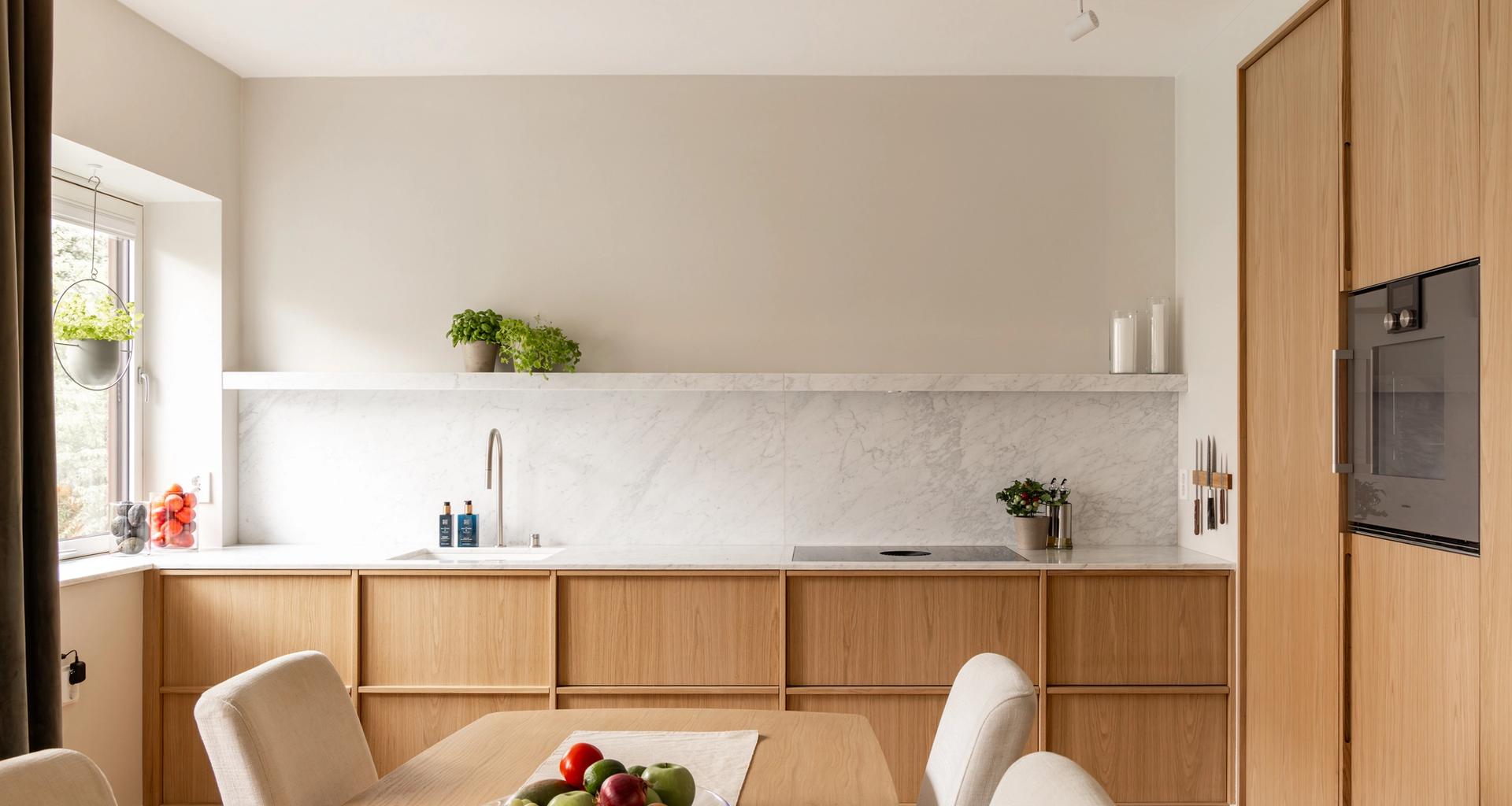Skandinavisk kjøkken i lyst tre og benkeplate med marmoreffekt. Kjøkkenet har en stilren og minimalistisk innredning, og et luftig uttrykk. Utført av Lomundal.