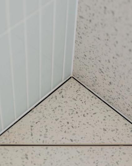 Detaljbilde av sluk i dusjsone, som er i samme terrazzoflis som gulvet. Dette gir et sømløst og helhetlig uttrykk. Badet er totalrenovert av Lomundal.