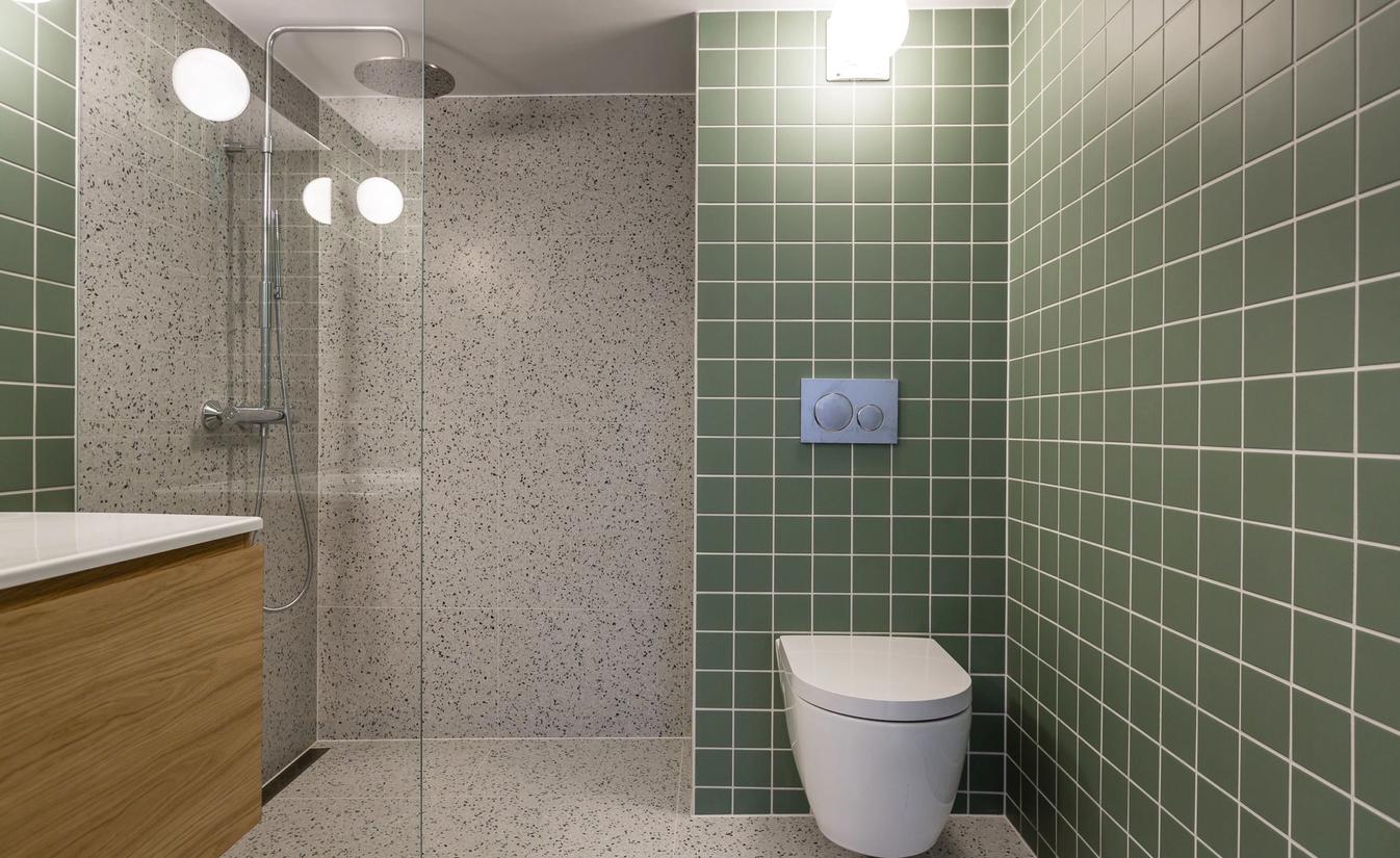 Retro bad med grønne fliser på vegg, fliser med terrazzo på gulv og dusjrom, utført av Lomundal.