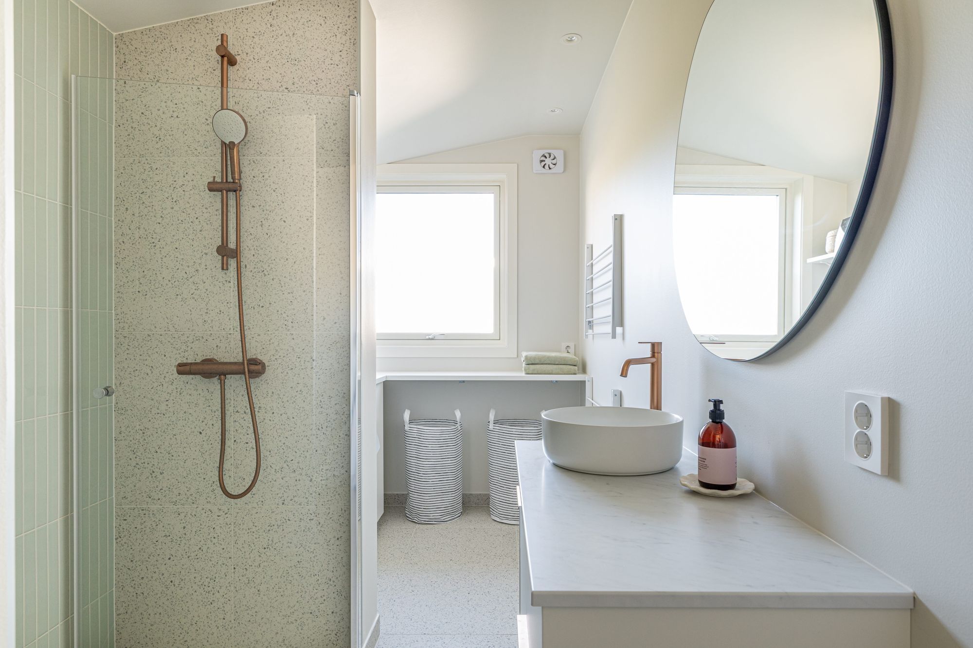 Oppussing av bad i en lys, minimalistisk stil. Rommet kombinerer nå bad og vaskerom, for en praktisk løsning for kundene. Det er også et vindu på badet som gir godt med naturlig dagslys. Badet er totalrenovert av Lomundal.