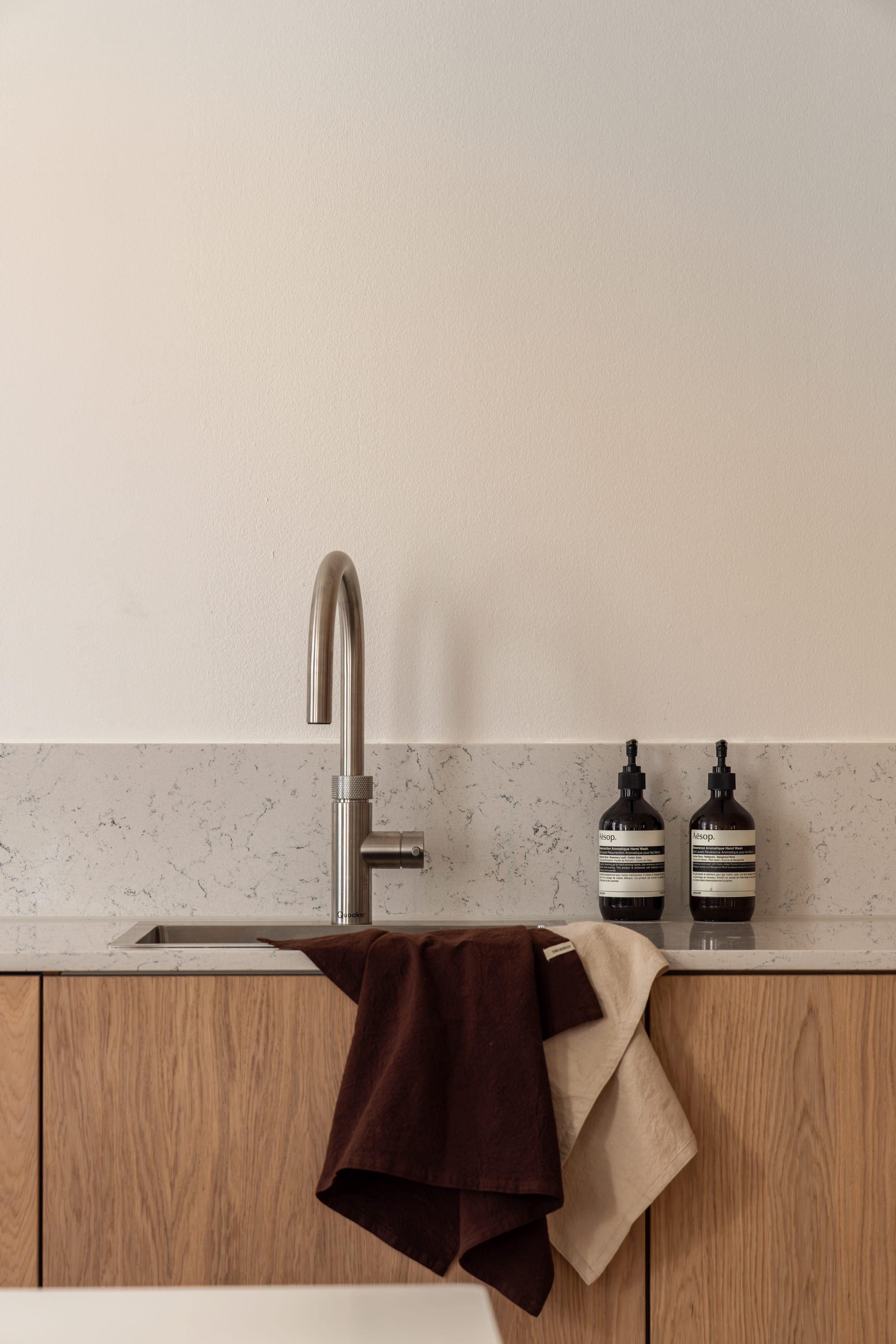Kjøkken i skandinavisk stil med innredning i eik og kompositt benkeplate og backsplash. Totalrenoveringen er utført av Lomundal.
