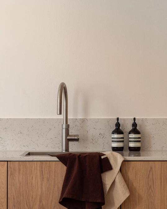 Kjøkken i skandinavisk stil med innredning i eik og kompositt benkeplate og backsplash. Totalrenoveringen er utført av Lomundal.