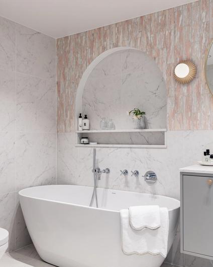 Eksklusivt, klassisk bad i lyse, delikate fargetoner. Badet er flislagt med norsk, rosa Fauske marmor og Carrara marmor. Badet har et frittstående badekar og en buet dusjnisje på vegg. Utført av Lomundal.