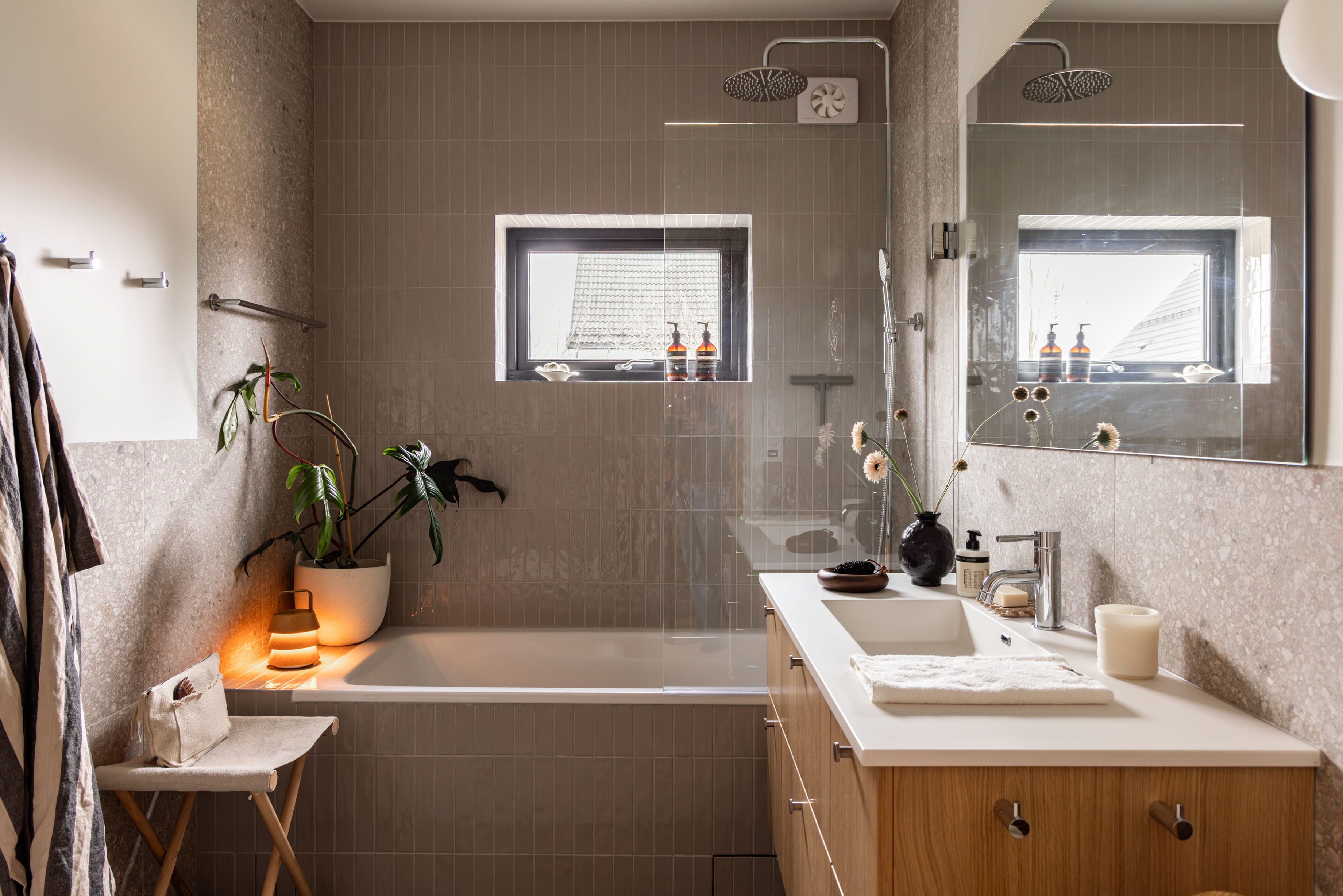 Master bad med blanke fliser i dusjsonen, terrazzofliser på vegg og baderomsinnredning i lyst treverk. Badet er totalrenovert av Lomundal.