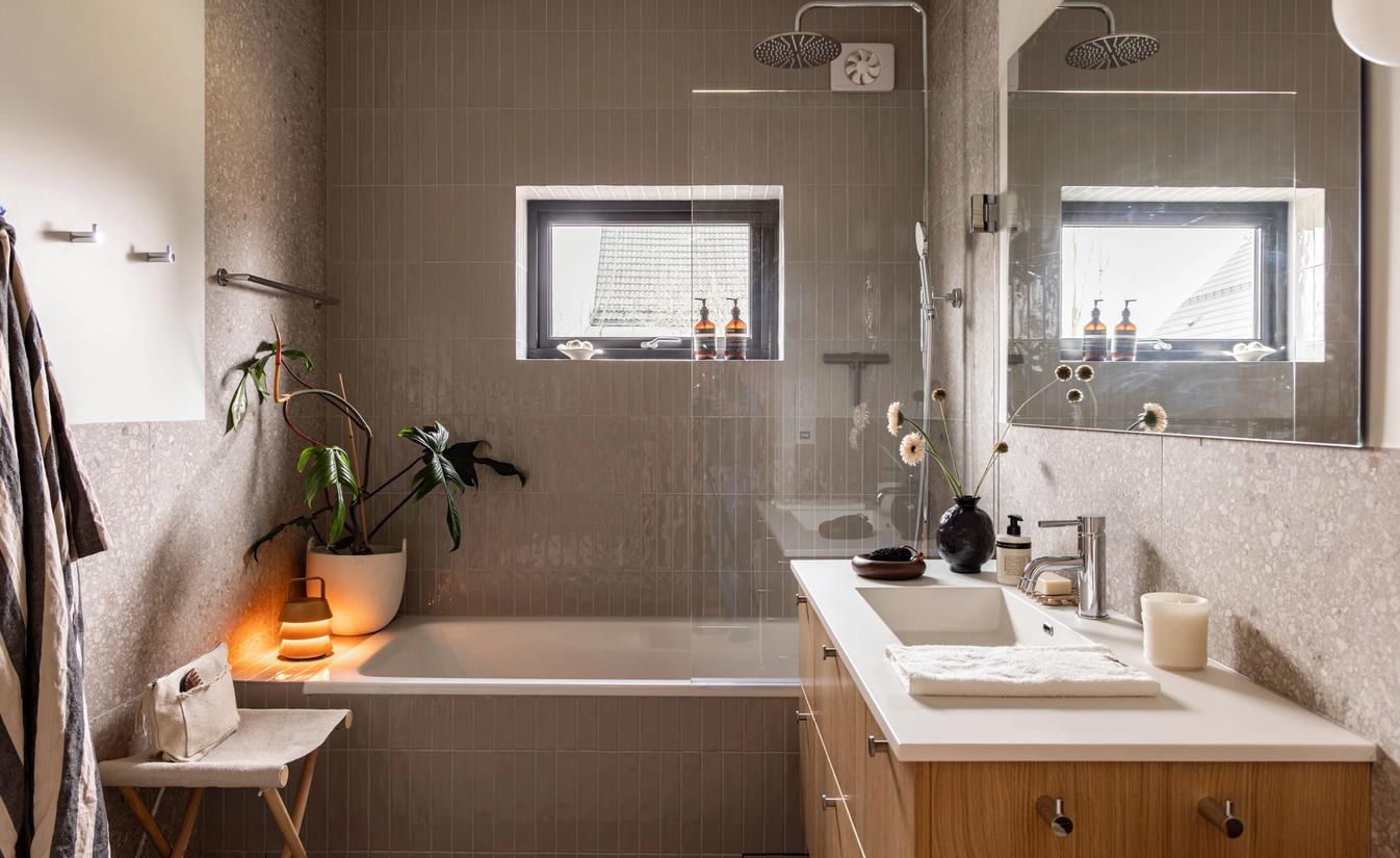 Master bad med blanke fliser i dusjsonen, terrazzofliser på vegg og baderomsinnredning i lyst treverk. Badet er totalrenovert av Lomundal.
