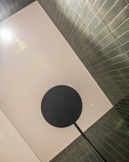 Detaljbilde av moderne dusjsone med populære blanke fliser i en lun grønnfarge. Utført av Lomundal.