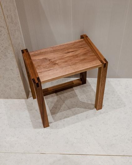 Detaljbilde på lyst og moderne bad med en krakk i mørkt tre.