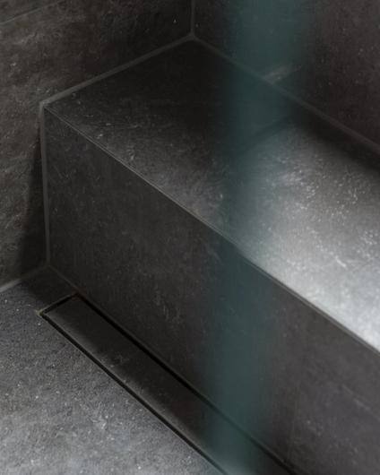 Detaljbilde av dusjrom med designsluk og trapp, utført av Lomundal.