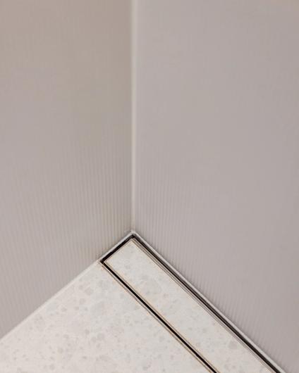 Detaljbilde i dusj med designsluk fra Purus med insert tile sluk. Badet er pusset opp av Lomundal.