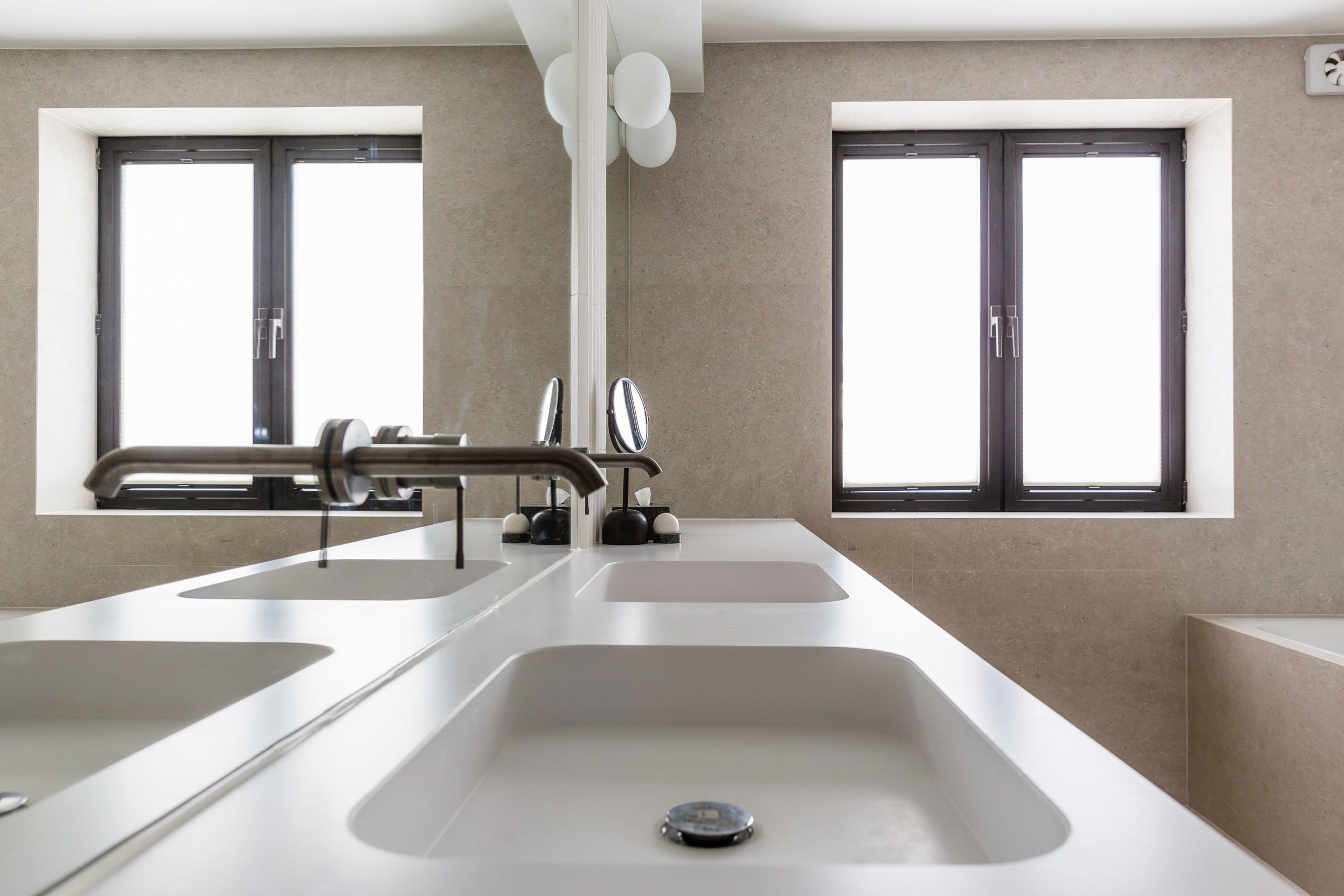Detaljbilde fra badet til Camilla Pihl med dobbel servant i kompositt, med innebygde armaturer montert på spesiallaget speil, utført av Lomundal.