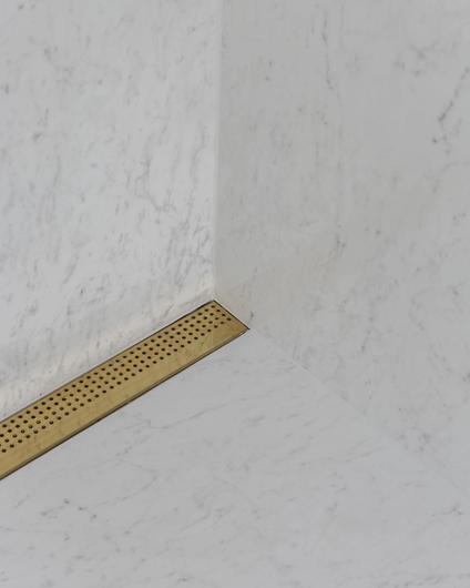 Detaljbilde av dusjrom med fliser i marmor og designsluk i messing, utført av Lomundal.