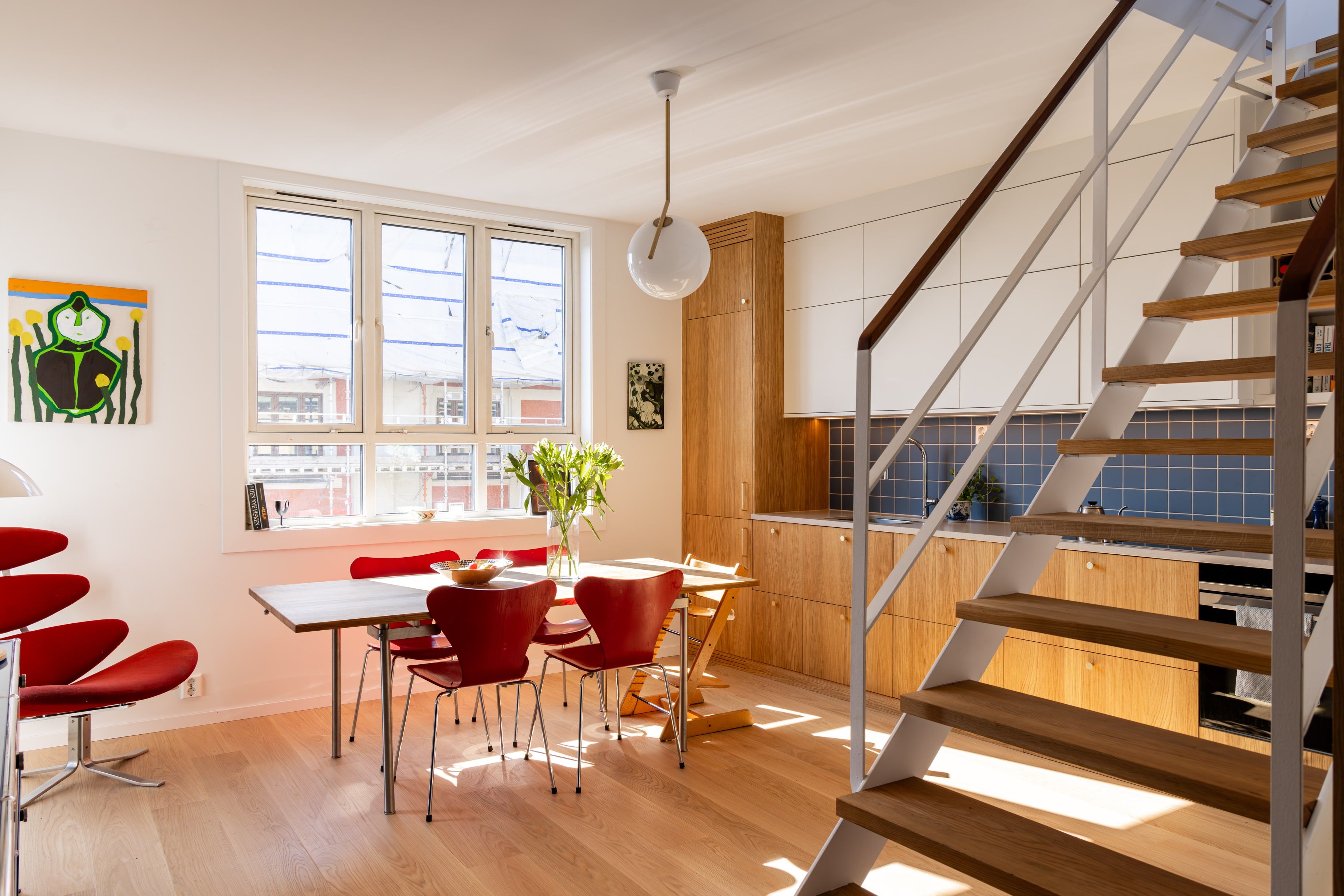 Moderne leilighet totalrenovert av Lomundal. Kjøkkenet er bygget av møbelsnekker med laminat og eikefinér med blå kvadratiske fliser som backsplash.