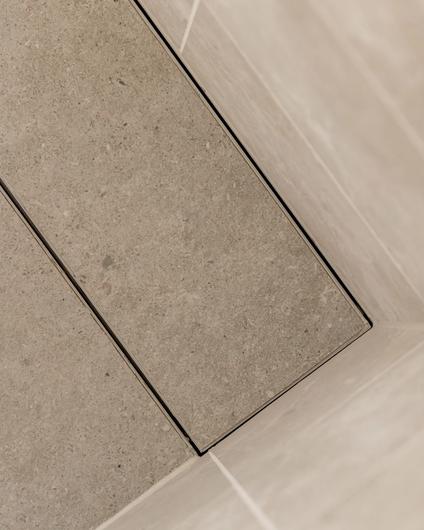 Detaljbilde av flislagt sluk i dusjsone. Totalrenoveringen er utført av Lomundal.