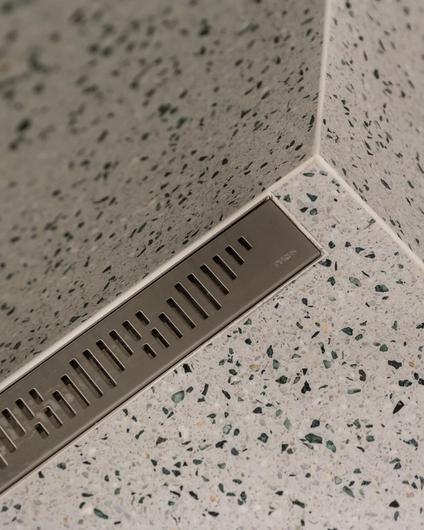 Detaljbilde av dusjrom med fliser i terrazzo og designsluk fra Purus, utført av Lomundal.