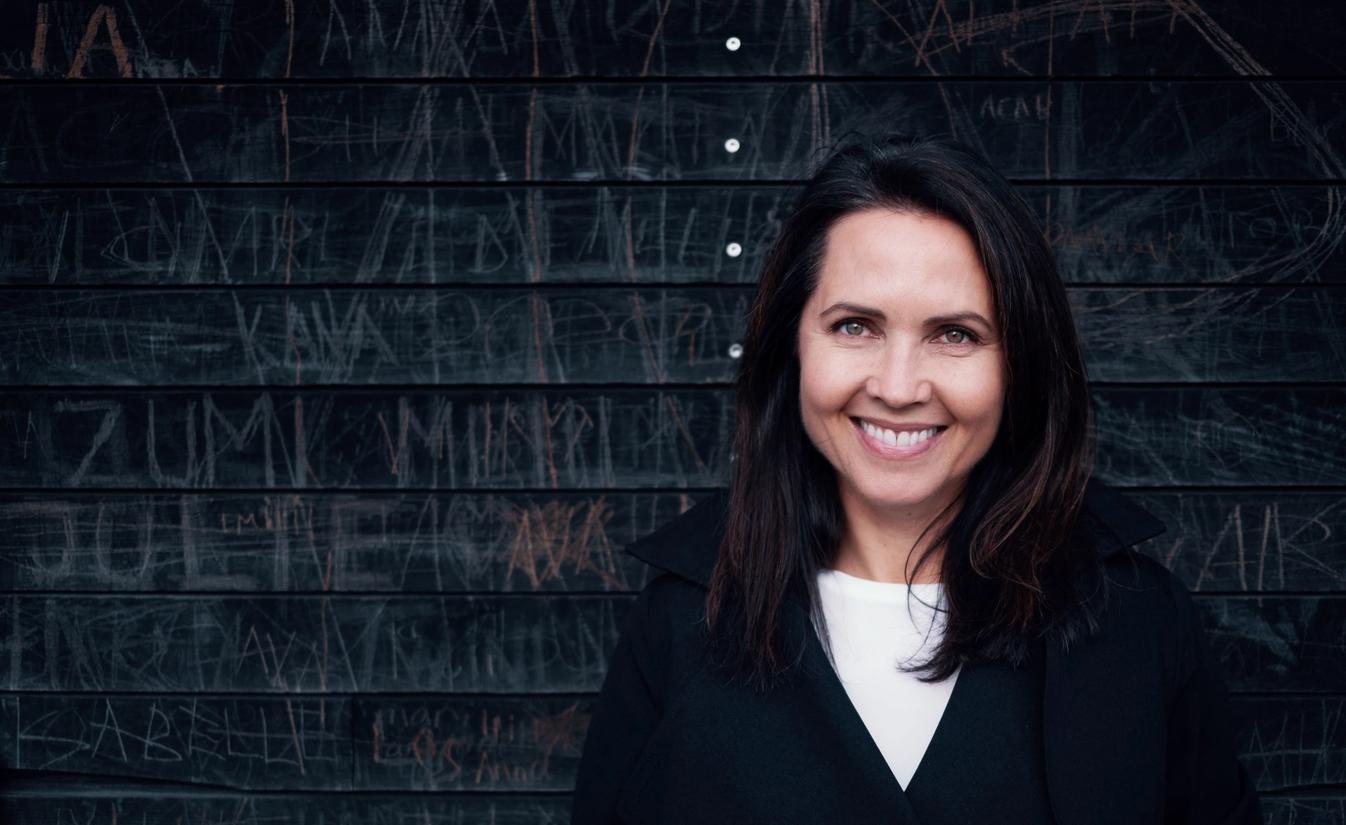 Renathe jobber i administrasjonen for Lomundal. Her står hun ute mot en mørk vegg og smiler.