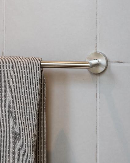 Detaljbilde av håndkleholder montert på flislagt vegg på bad. Utført av Lomundal.