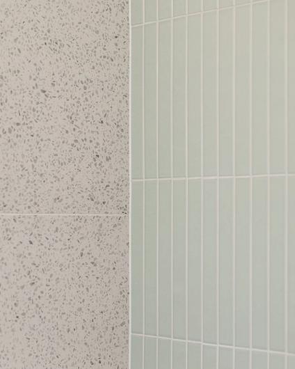 Detaljbilde av fliser i dusjsone. En organisk kombinasjon av terrazzoinspirert flis og en blank, mintgrønn dekorflis. Badet er totalrenovert av Lomundal.