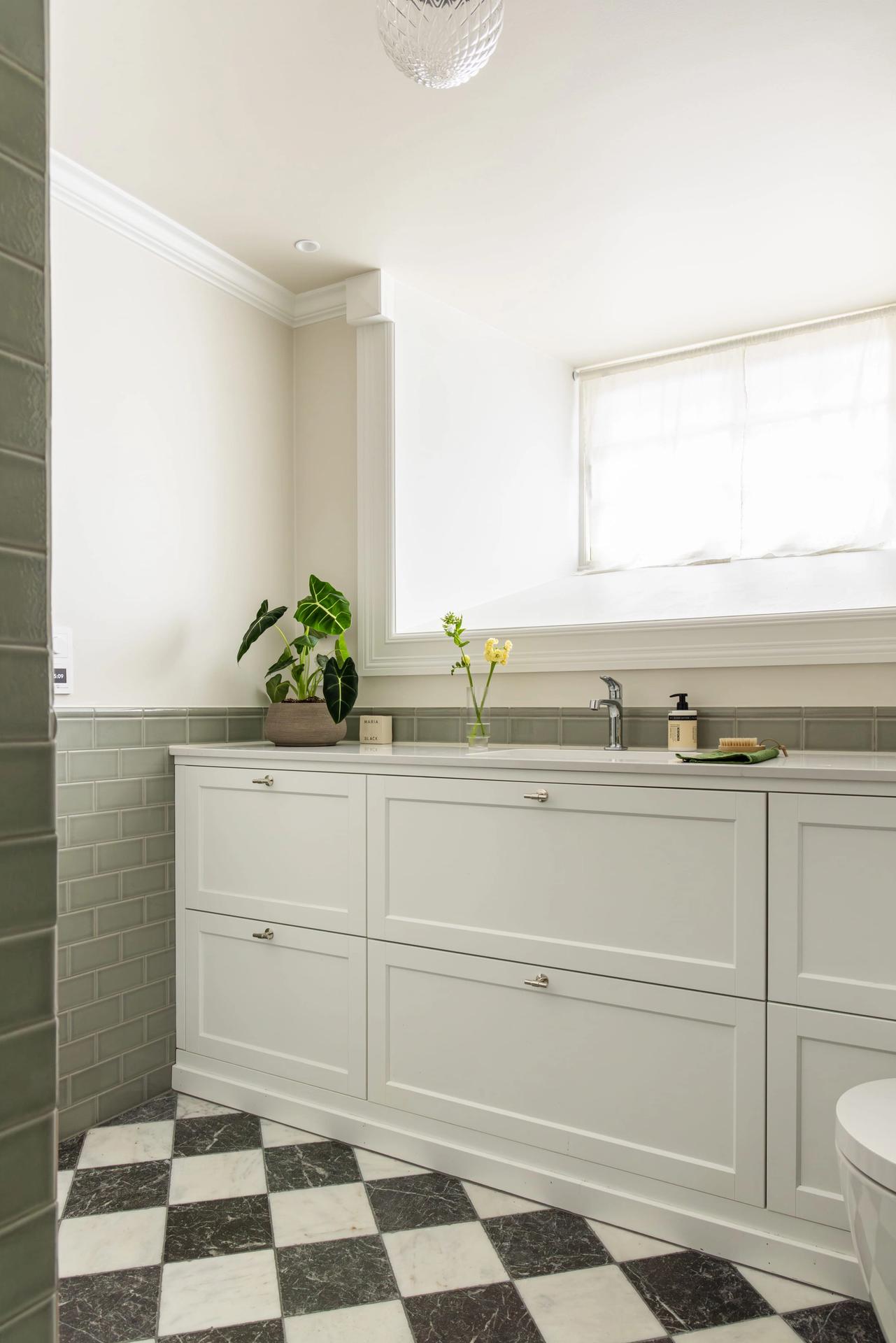 Klassisk baderomsinnredning med profilerte fronter og benkeplate i stein. Badet har et klassisk og elegant uttrykk, med et tidløst fargepalett. Utført av Lomundal. - Bilde