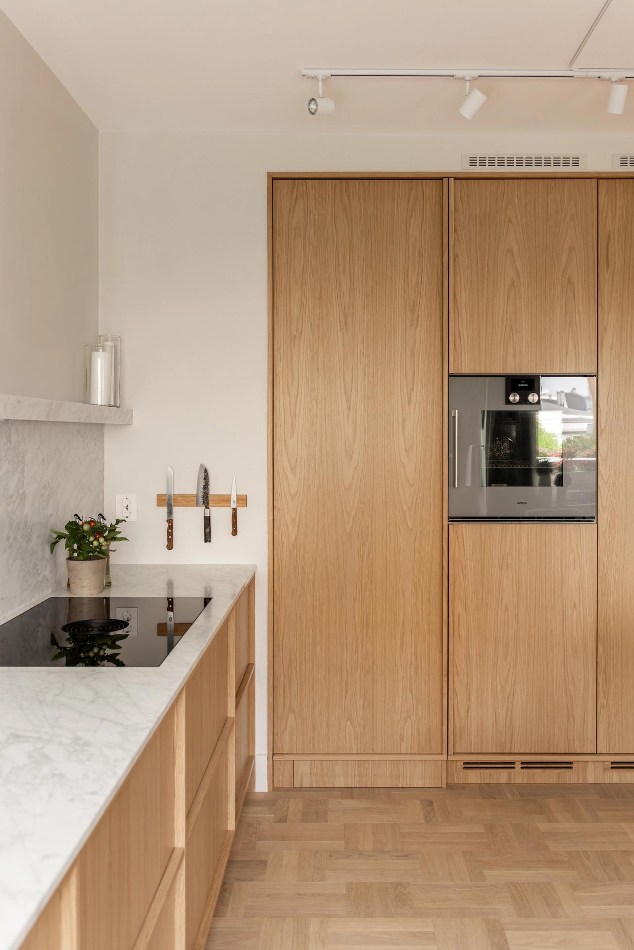 Skandinavisk kjøkken i lyst tre og benkeplate med marmoreffekt. Kjøkkenet har en stilren og minimalistisk innredning, og et luftig uttrykk. Utført av Lomundal. - Bilde
