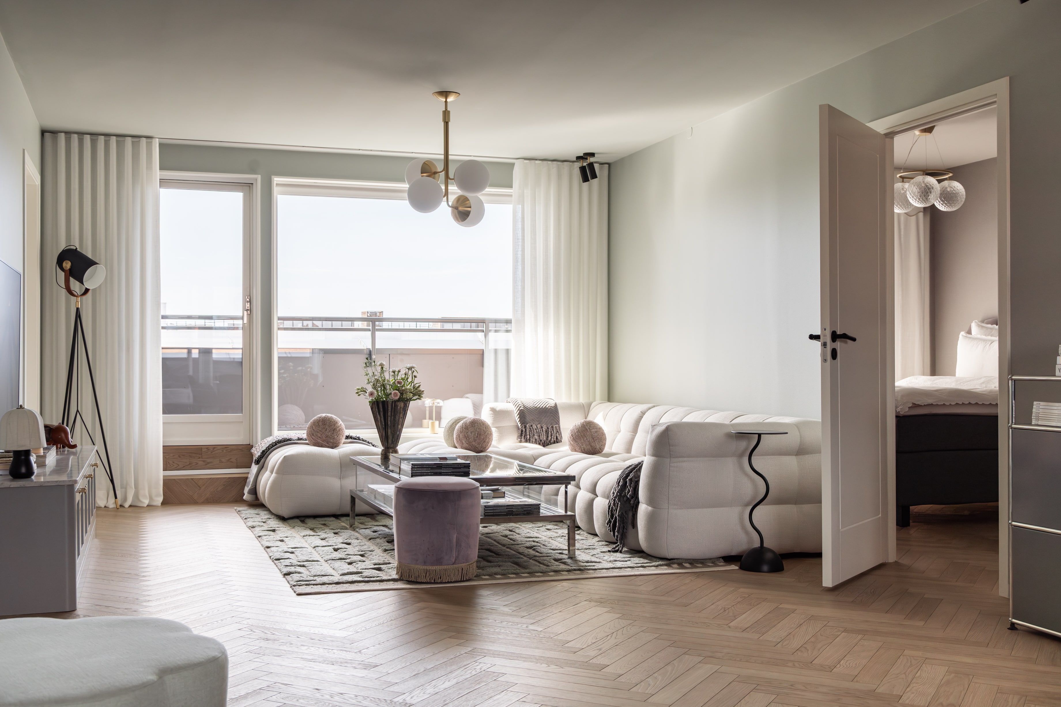 Moderne stue med innredning i lyse toner og en vegger i en dempet mintgrønn tone. Gulvet er en lys eikeparkett med fiskebensmønster. Utført av Lomundal.