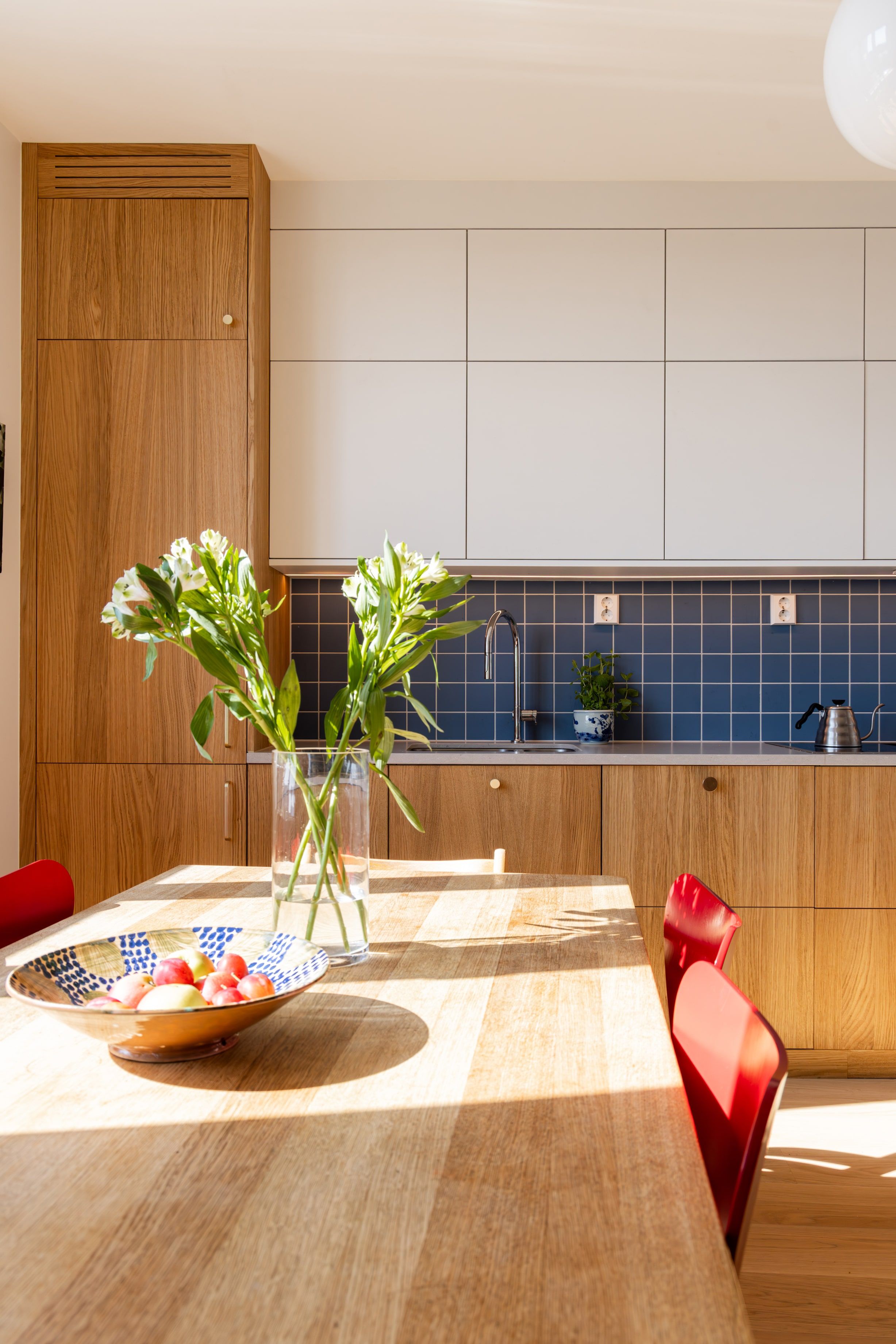 Moderne leilighet totalrenovert av Lomundal. Kjøkkenet er bygget av møbelsnekker med laminat og eikefinér med blå kvadratiske fliser som backsplash.