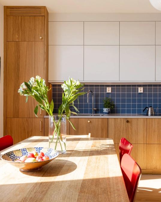 Moderne leilighet totalrenovert av Lomundal. Kjøkkenet er bygget av møbelsnekker med laminat og eikefinér med blå kvadratiske fliser som backsplash.