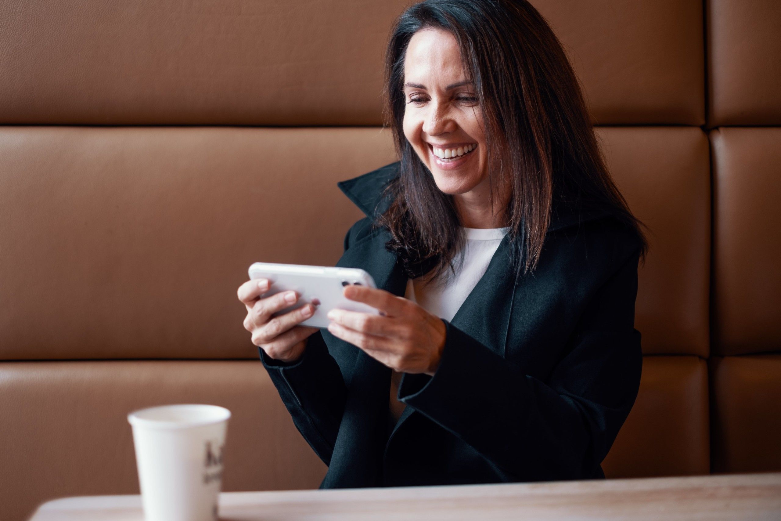 Renathe sitter på kafe og ser på noe på telefonen. Hun jobber i administrasjonen hos Lomundal.