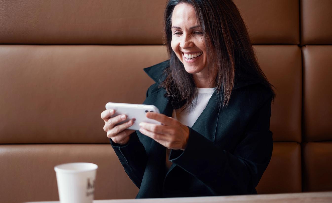 Renathe sitter på kafe og ser på noe på telefonen. Hun jobber i administrasjonen hos Lomundal.