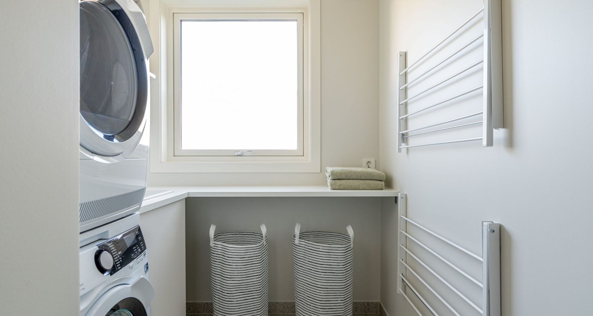 En egen sone for vaskerom inne på et nyoppusset bad. Her har kundene fått godt med arbeidsplass og dagslys, og plass til både vaskemaskin og tørketrommel. Vaskerommet står i stil til resten av badet, med malte flater i Jotuns farge Sommersne, og terrazzoflis på gulv. Badet er totalrenovert av Lomundal.