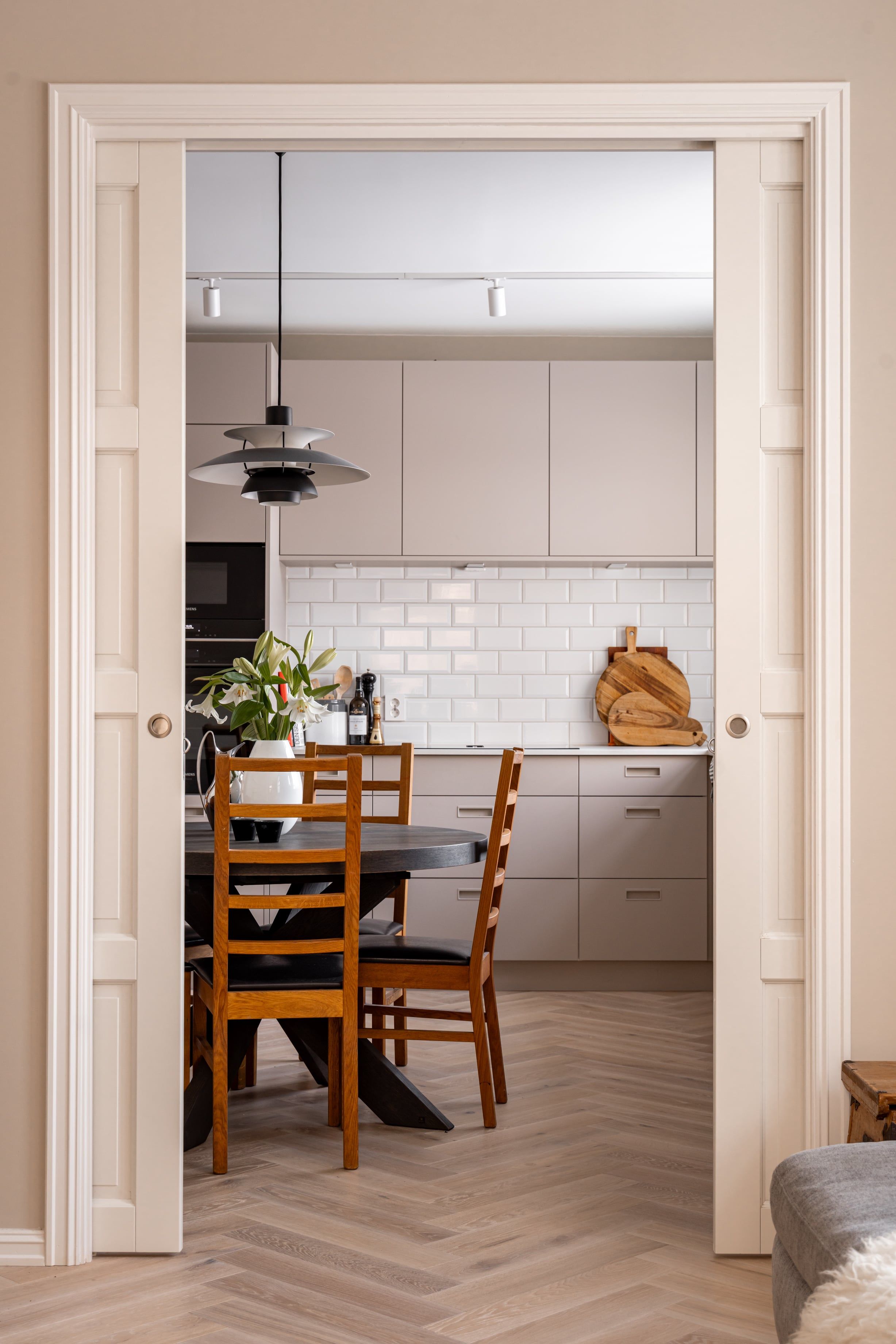 Lyst og moderne kjøkken med fiskebensparkett og beige kjøkkeninnredning. Utført av Lomundal.