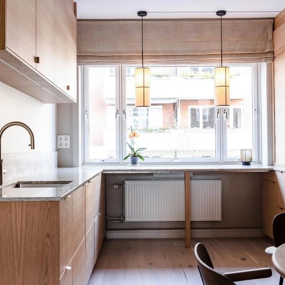 Kjøkken i eik fra Drømmekjøkkenet med grå og hvit benkeplate i stein. Taklamper ved vindu fra Menu. Kjøkkenet er totalrenovert av Lomundal.