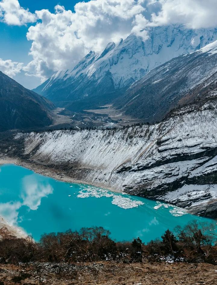 Der türkisfarbene Birendra See mit Eisschollen unterhalb des Manaslu-Gletschers bei Samagaon, dahinter das Tal des Budhi Gandaki und schneebedeckte Grate