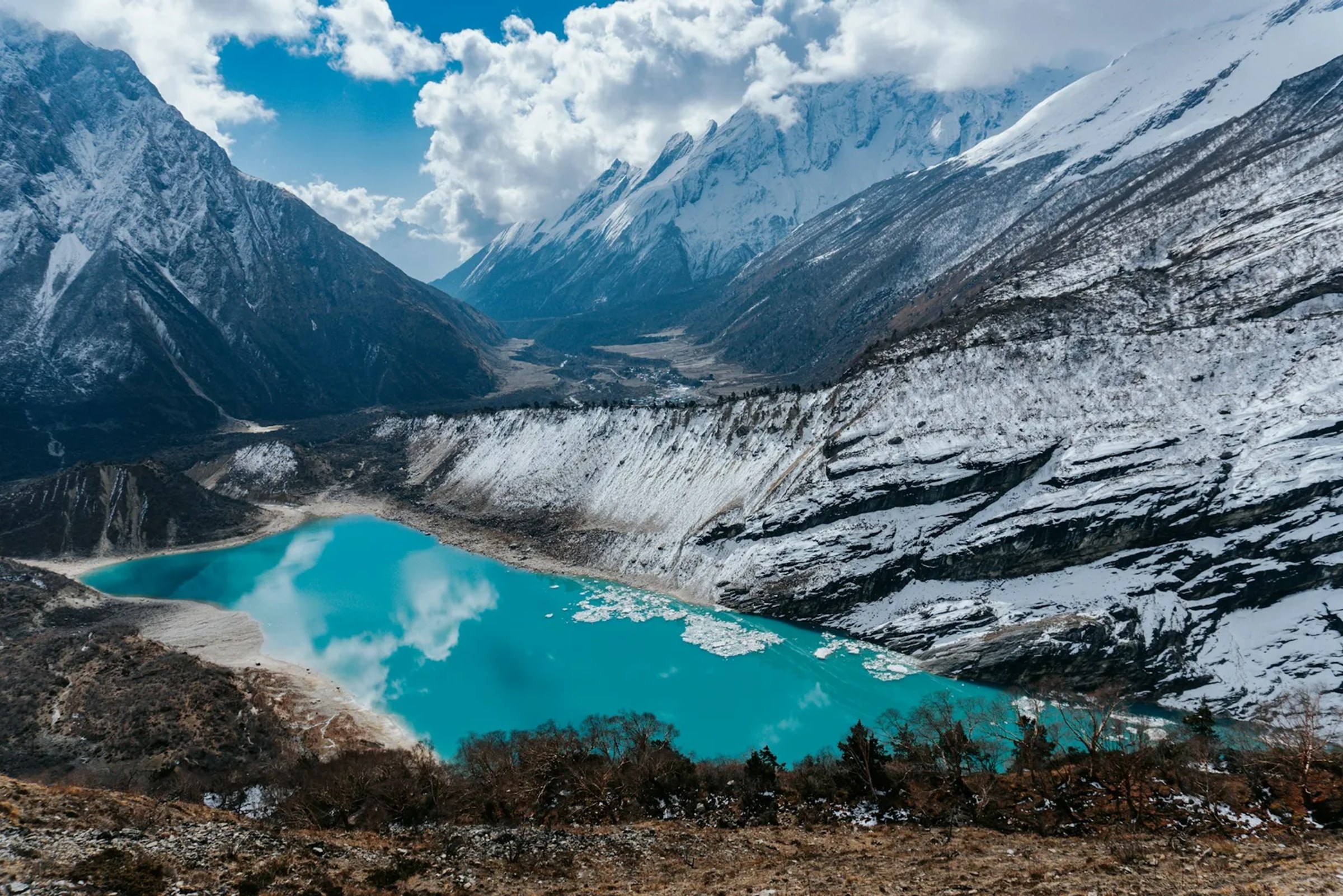 Der türkisfarbene Birendra See mit Eisschollen unterhalb des Manaslu-Gletschers bei Samagaon, dahinter das Tal des Budhi Gandaki und schneebedeckte Grate