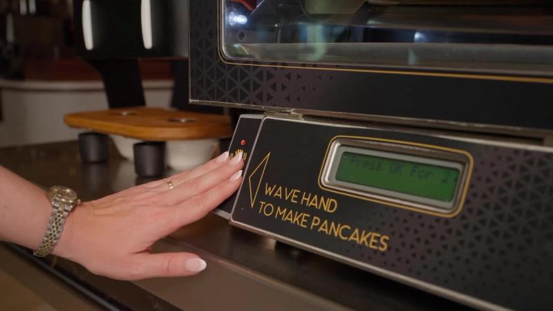 Een gast wuift met haar hand langs de sensor van de pancake machine