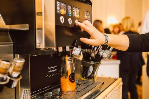 Gast tapt vruchtensap uit de dispenser op het ontbijtbuffet
