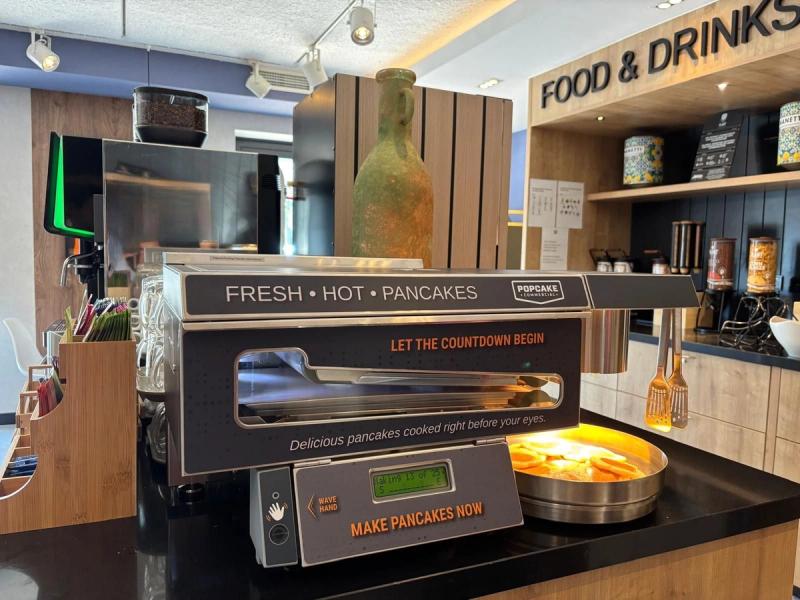 De Popcake pancake machine op een ontbijtbuffet, met broodmanden en fruit ernaast