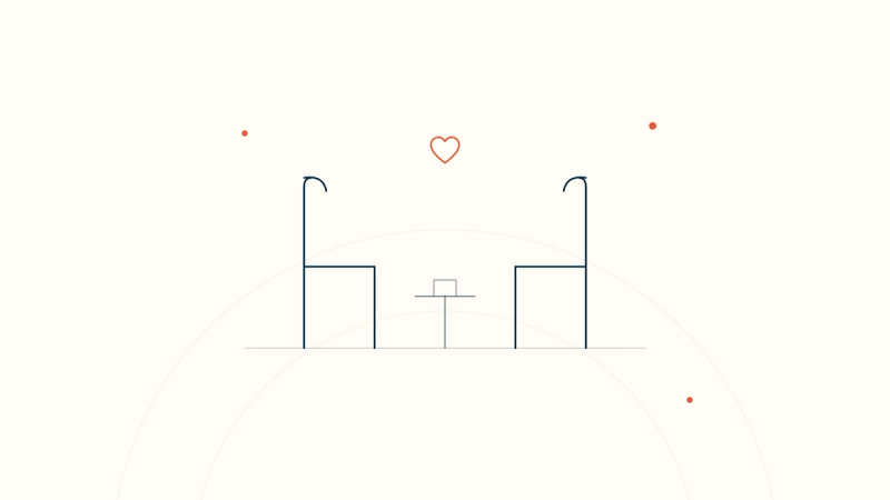 Two chairs facing each other with a small table between them and a heart above — presence in palliative care conversations.