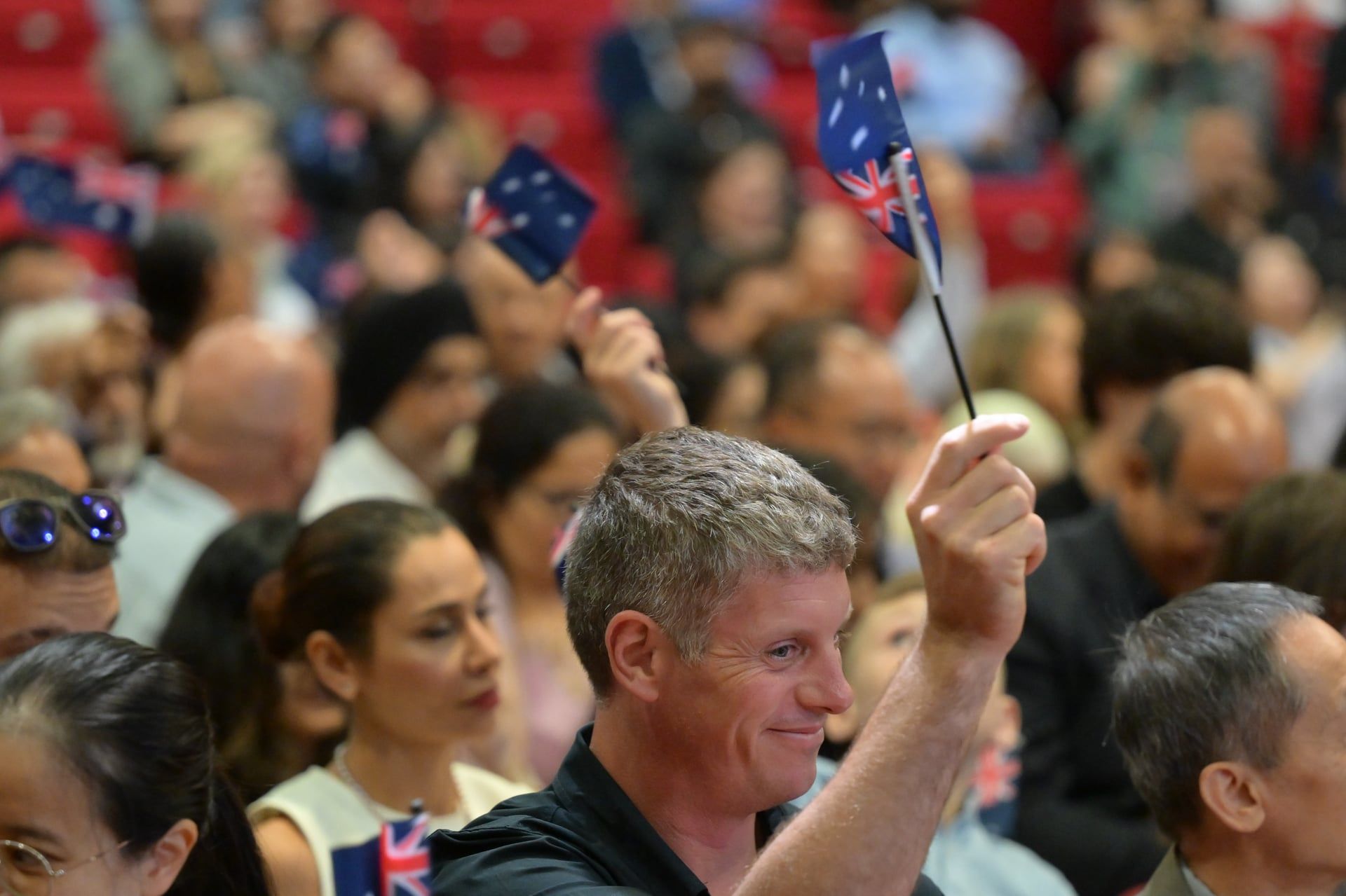 New Australian citizens waving Australian flags at Hills Shire Council citizenship ceremony