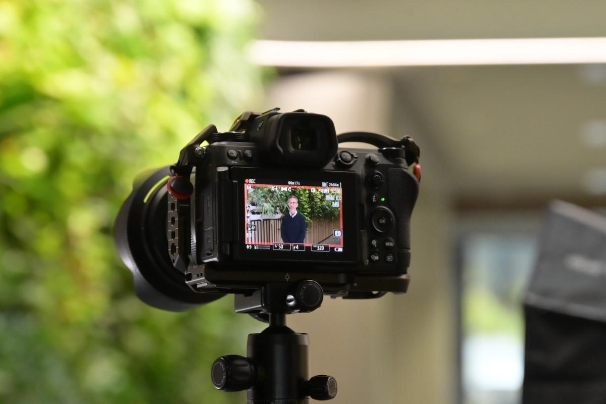 Camera monitor showing the presenter framed during a government video shoot