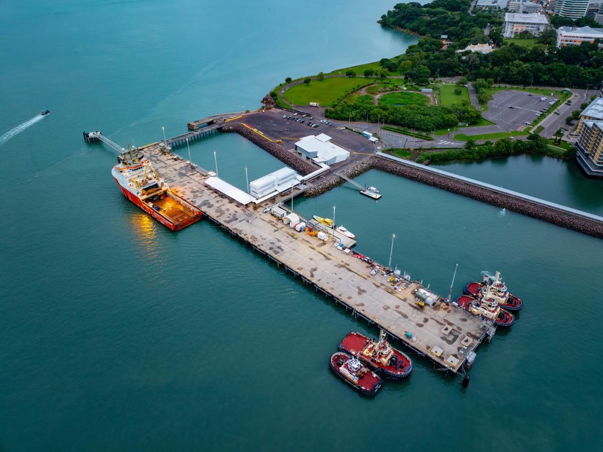 Aerial view of Darwin wharf with a red supply vessel docked alongside and tugboats moored at the end, Northern Territory.