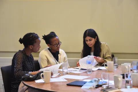Three workshop participants sitting at a table looking at notes.