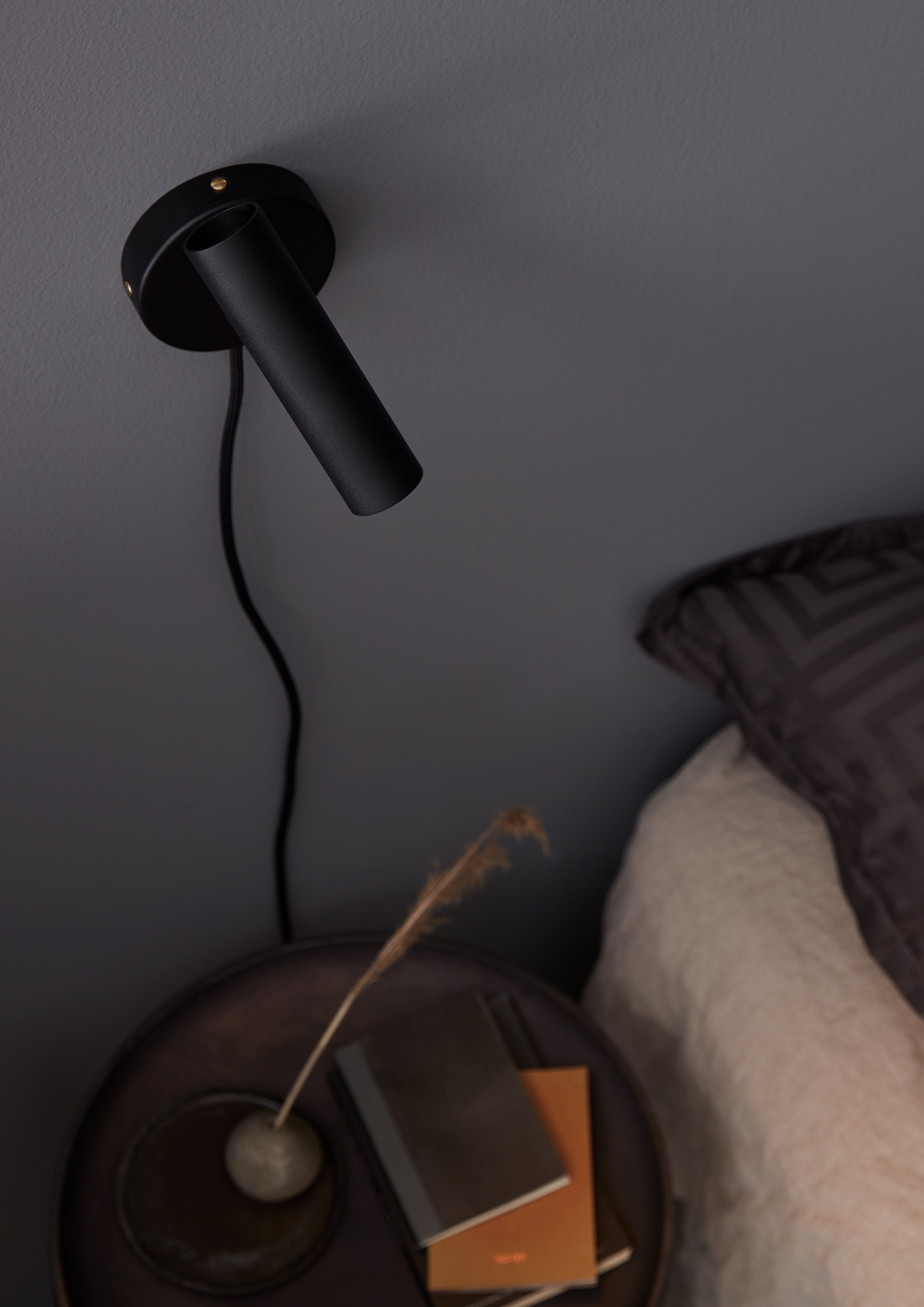 Black wall lamp beside the bed 