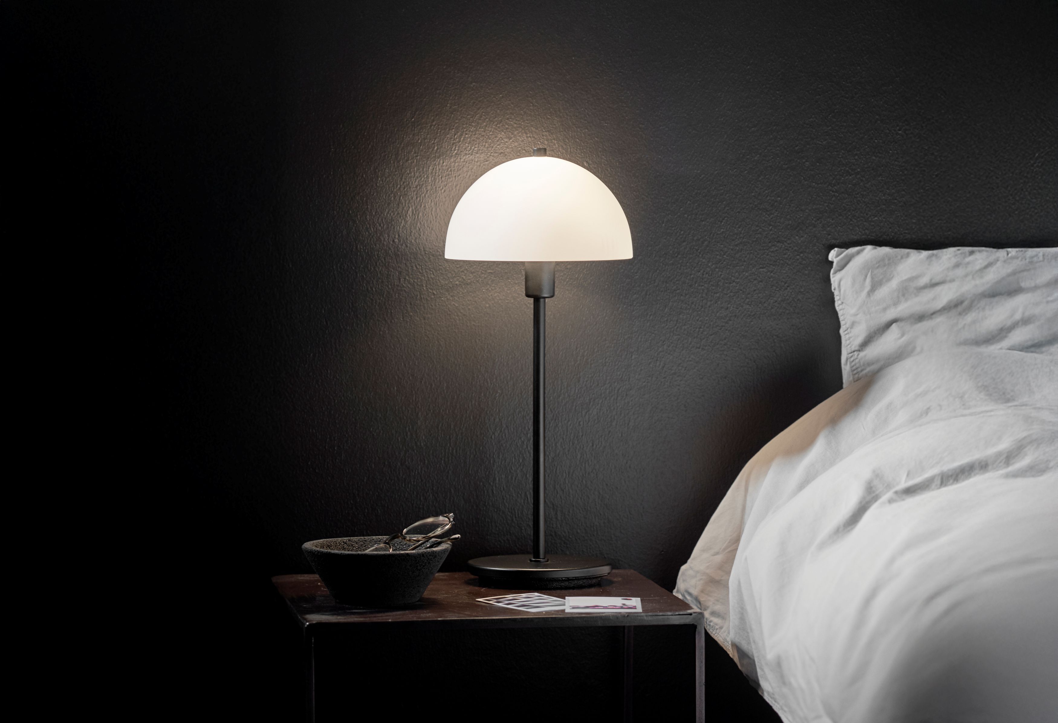 Black table lamp beside bed