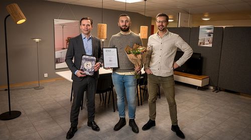 Three men holding flowers and awards