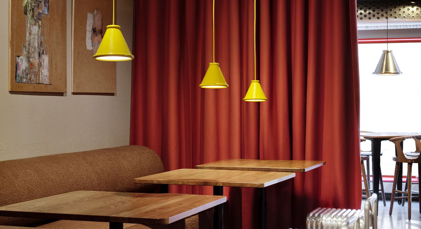 Gula Belle-pendlar från Belid Lighting Group som belyser träbord och metallstolar på restaurang Blokk i Göteborg. 