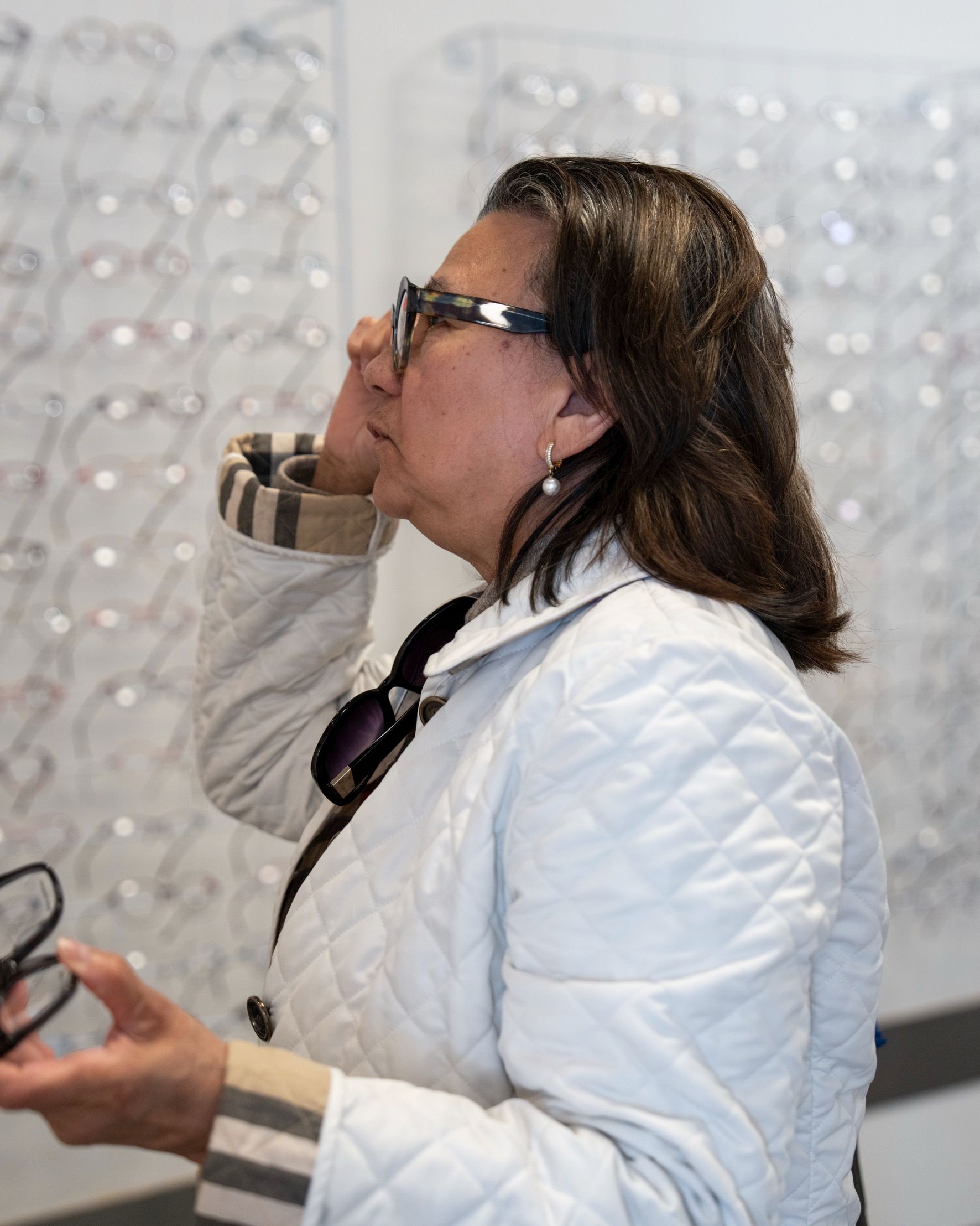 Person der prøver forskellige brillestel hos optiker for at finde den rigtige pasform