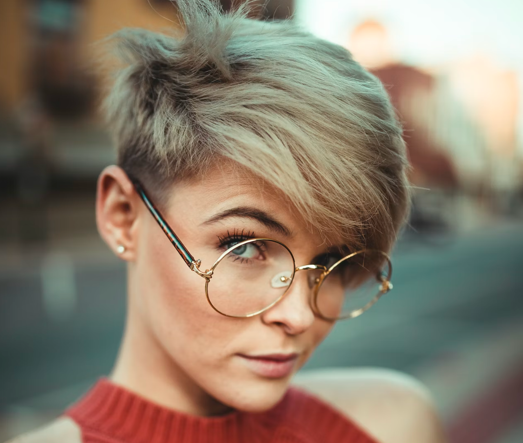 Kvinde med kort pixie cut og stilfulde briller der fremhæver hendes ansigtstræk