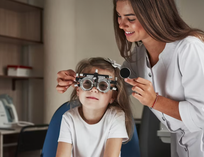 Optiker hjælper lille pige med at prøve forskellige børnebrillestel i farverig optikerbutik