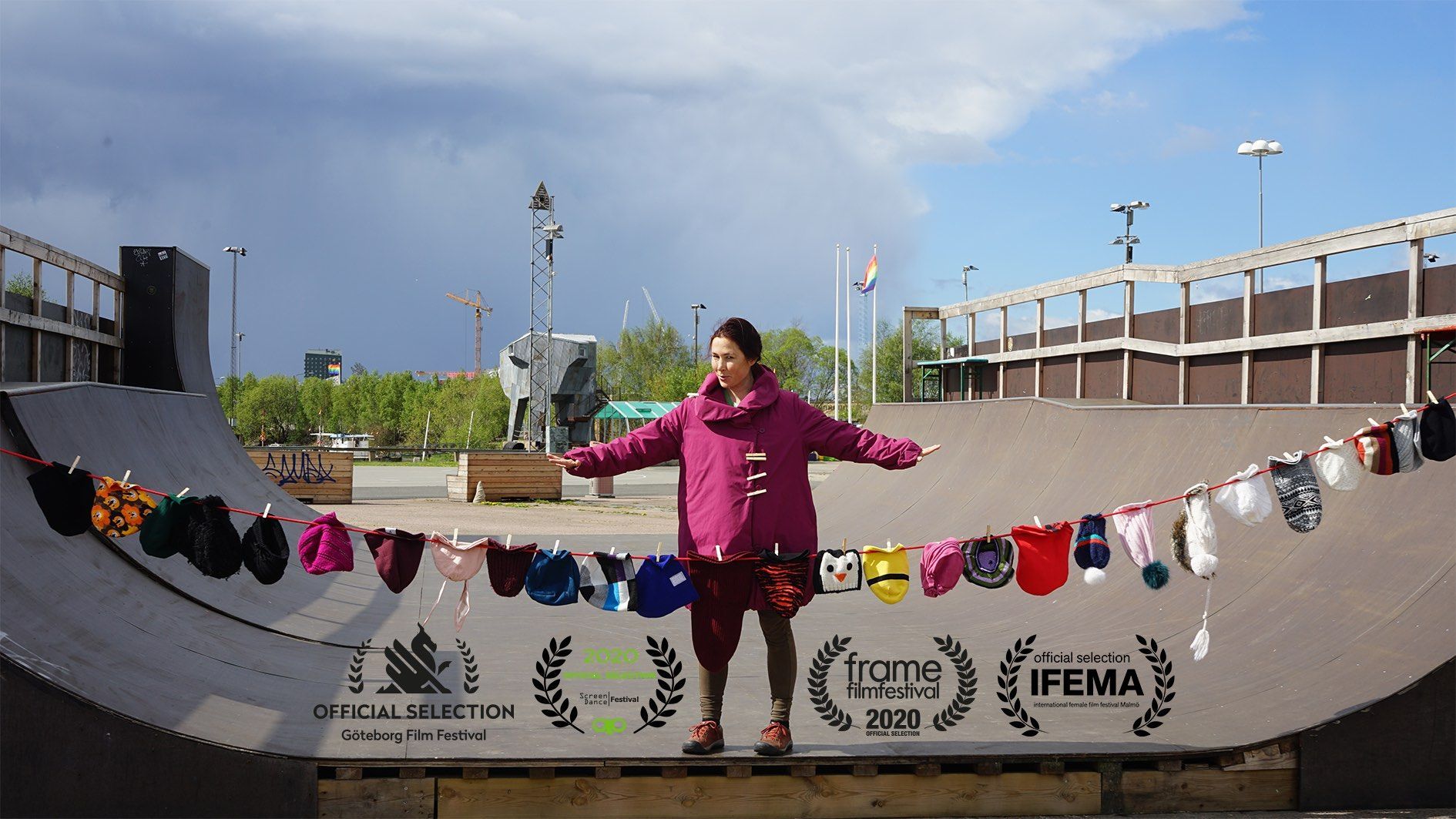 Stine står med utsträckta armar på en skateramp, med tvättlinor av små barnplagg uppspända framför sig.